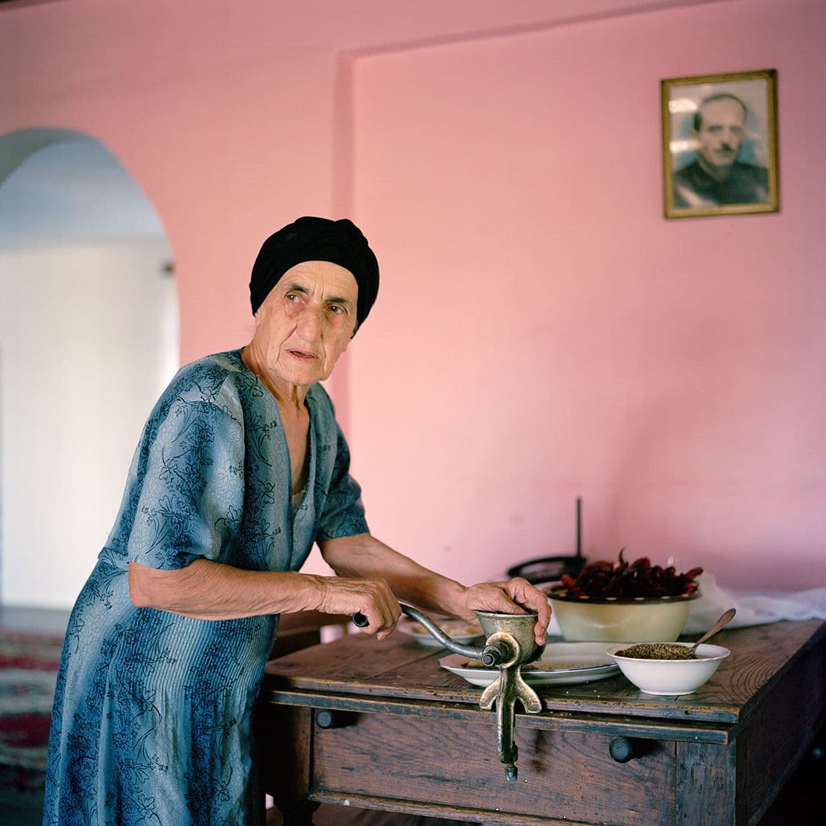 Ivor Prickett, "La madre di Tengo Inalishvili prepara una pasta piccante di peperoncini secchi nella casa della famiglia Inlaishvili nel villaggio di Rechxi." 2010, Rechxi, Abkhazia, Fotografia dalla serie “Returning Home – Abkhazia” © Ivor Prickett  